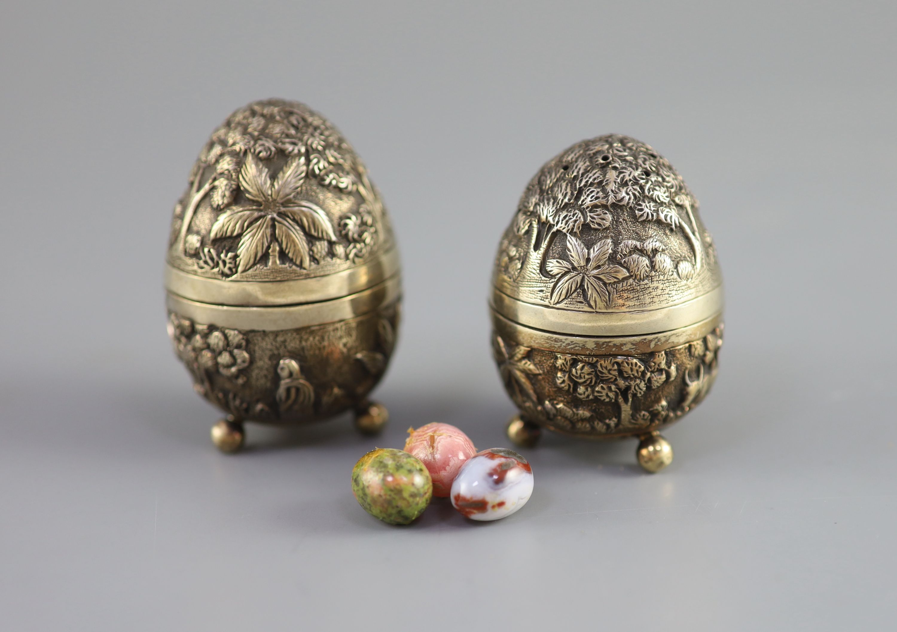 A graduated pair of Edwardian novelty silver gilt condiments, modelled as eggs, with bird's nest interior including two 'marbled' eggs